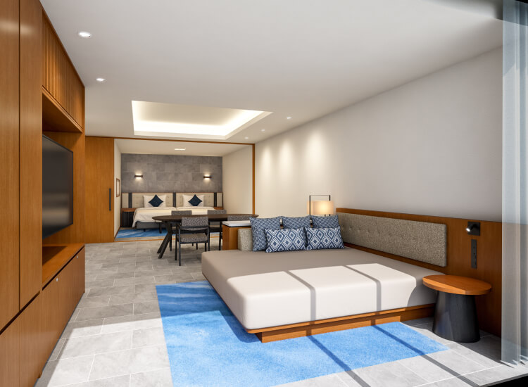 スタイリッシュなベッドルームで、手前にテレビ、奥には小さなダイニングエリアが見える。モダンな雰囲気の中に青いアクセントが配置されている。