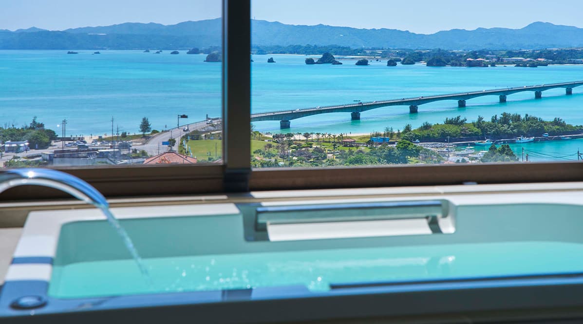 広々としたオーシャンビューの浴室から、青い海と、海にかかる長い橋、そして遠くの山々が見渡せる。