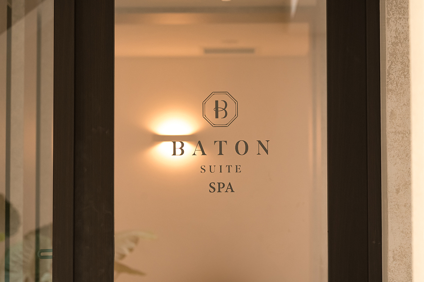 『BATON SUITE SPA』と書かれた、ガラス扉のスパ入口。扉の向こう側は温かい間接照明で照らされており、落ち着いた雰囲気を醸し出している。